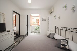 A bedroom with a bed, a dresser, a television, and a window with a view of the outside. - B-live by Ghor (Rome)