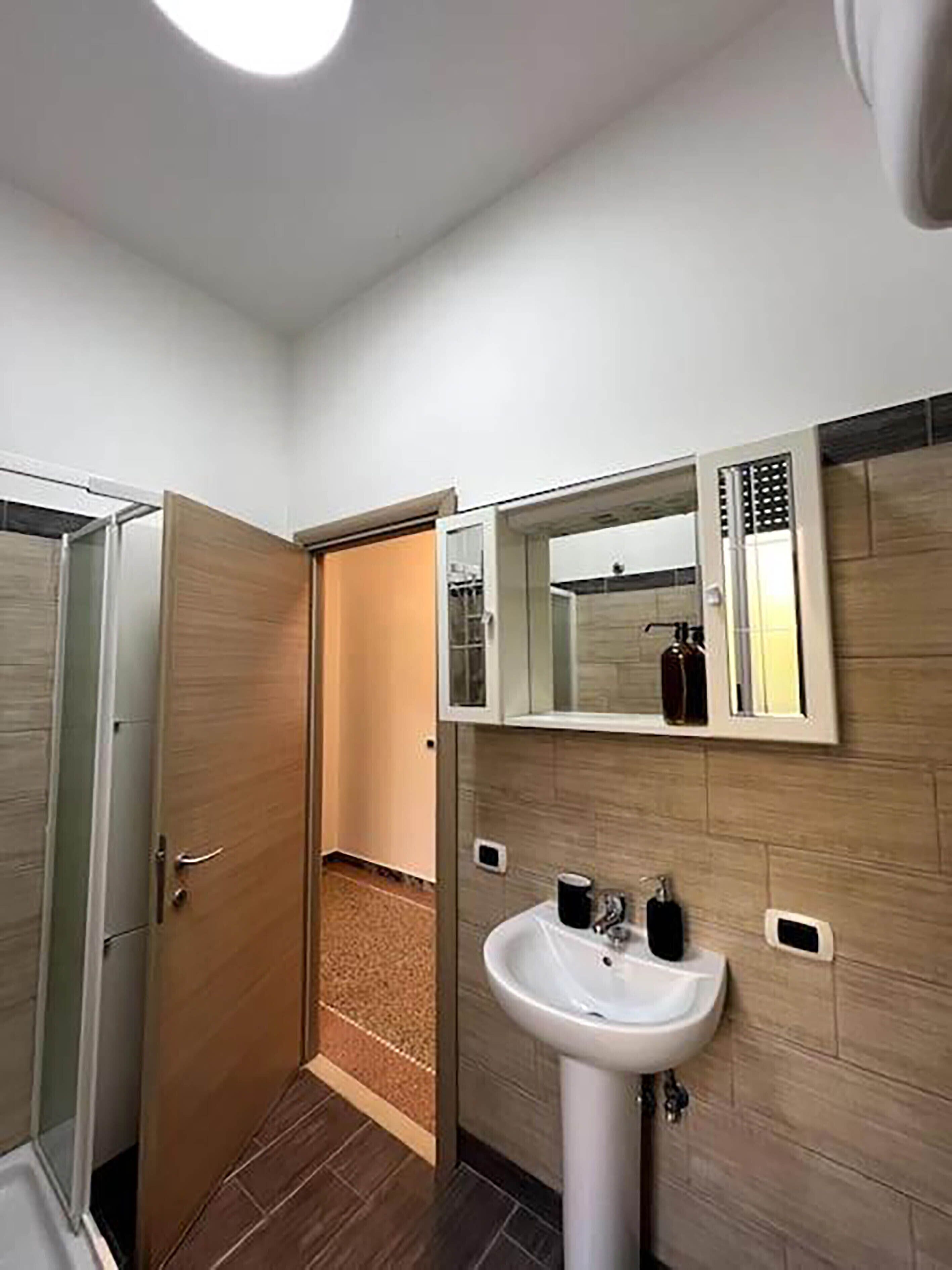 Een badkamer met een wit wastafel, een spiegel erboven en een houten deur.