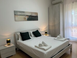 A modern bedroom with a large bed, two bedside tables with lamps, a painting on the wall, and a window with sheer curtains. - Planny Apartment - Vaticano by Ghor (Rome)