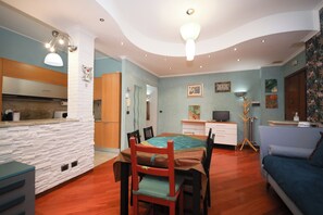 Un espacio habitable compacto con zona de comedor, kitchenette y sofá.