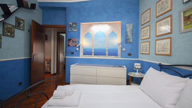 A hotel room with a bed, a nightstand, a window with a view, and artwork on the walls. - Archidee by Ghor (Rome)