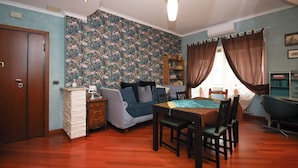 A cozy room with a wooden dining table, a sofa, and a bookshelf. - Archidee by Ghor (Rome)