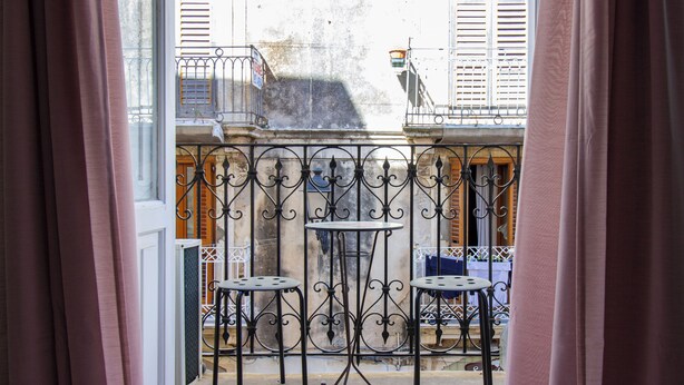 En balkon med jerngittermøbler og udsigt til bygninger.