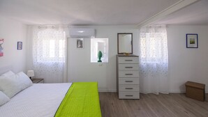Quarto com cama, penteadeira, janela e ar condicionado.