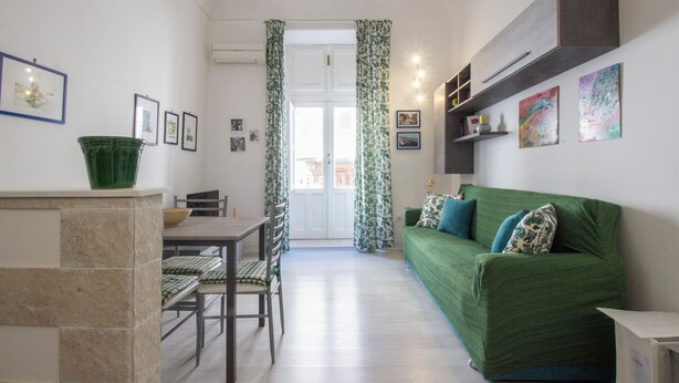 Um espaço de estar compacto com área de refeições, sofá verde e bancada de cozinha.