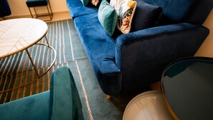 A blue sofa with patterned cushions, a round table, and a striped rug in a room. - Amate Case by Ortigia Apartments (Syracuse)