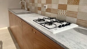 A kitchen with a gas stove, a sink, and a patterned backsplash. - Amate Case by Ortigia Apartments (Syracuse)