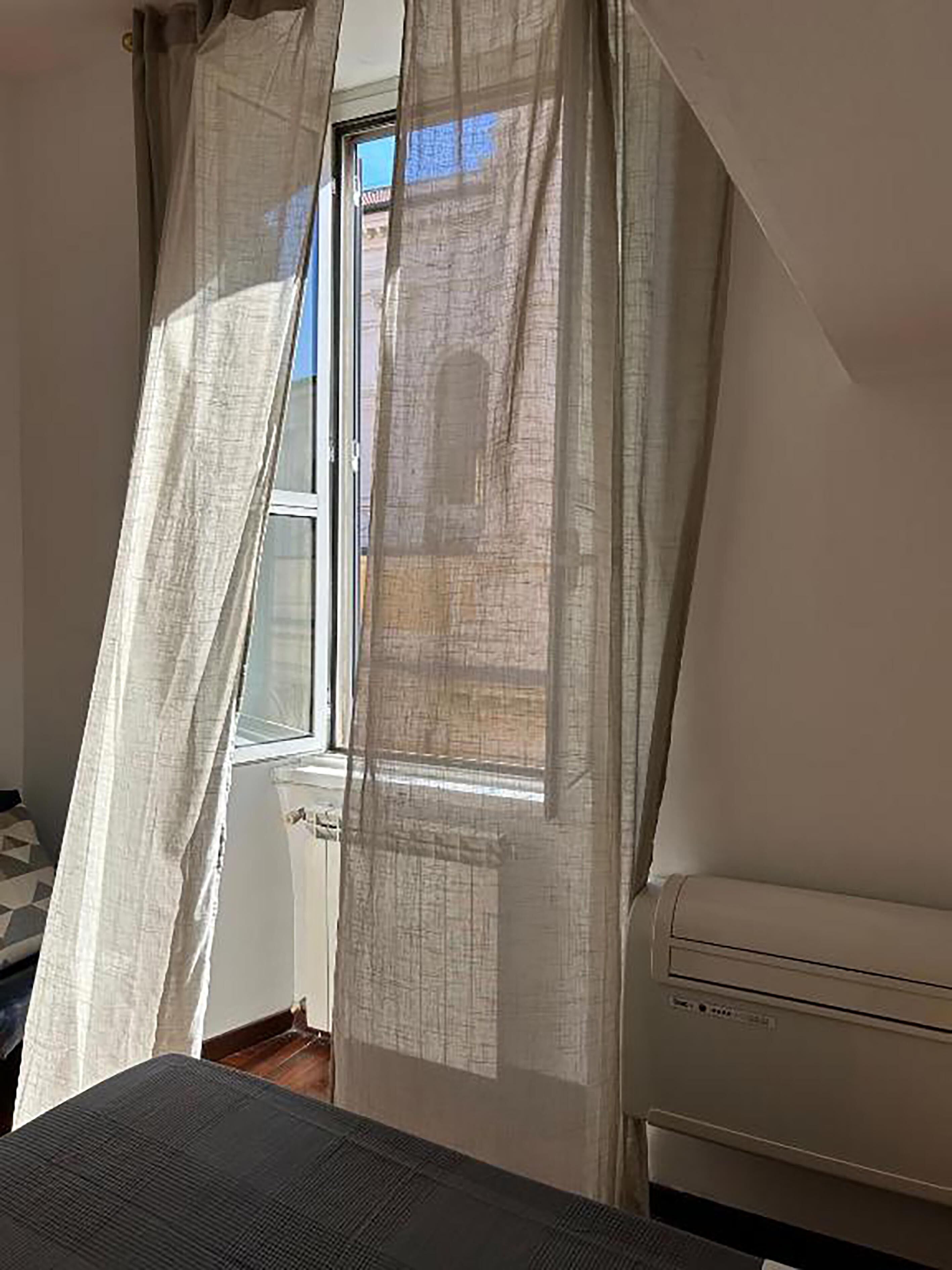 A room with a window, a radiator, and a bed.