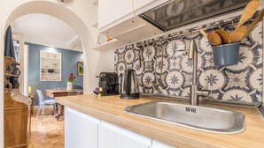 A kitchen with a wooden countertop, stainless steel sink, and a backsplash with blue and white tiles. - Spagna Suite Dream by Ghor (Rome)