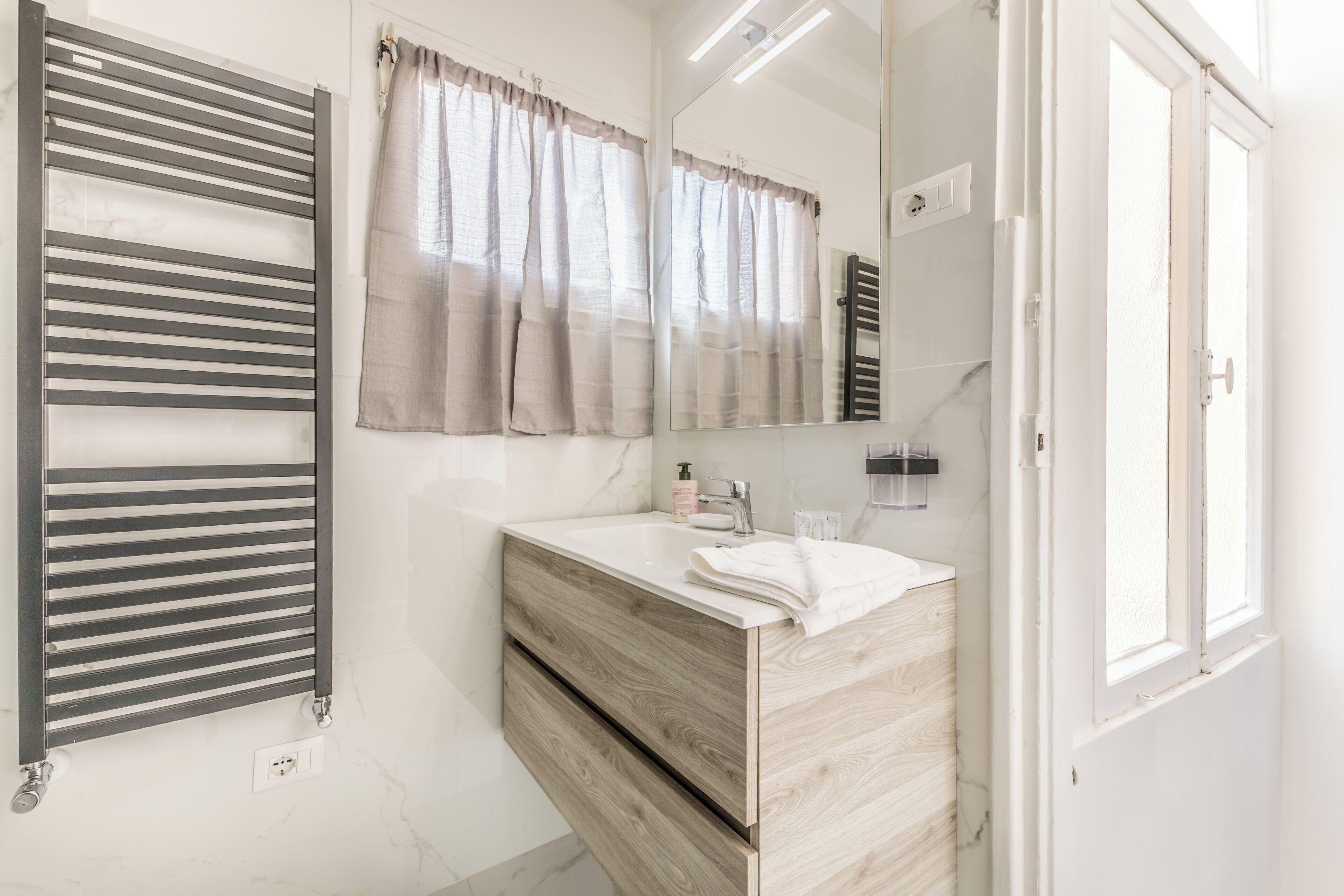 Une salle de bain moderne avec un meuble-lavabo en bois, une serviette, un miroir et un porte-serviettes.