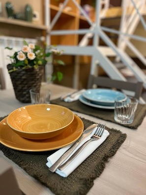 Une table à manger dressée avec une assiette marron, une assiette bleue, un verre et des couverts, le tout posé sur un set de table en fibres tressées.