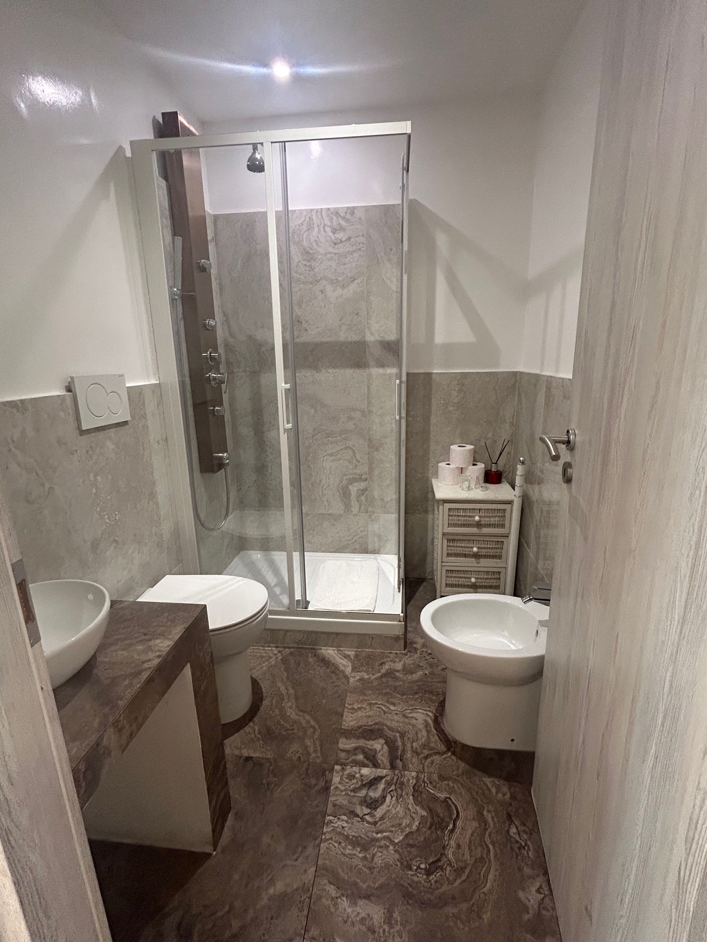 A modern bathroom with a glass-enclosed shower, two sinks, and a vanity with a mirror.