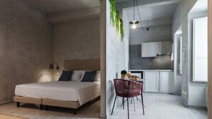 Un dormitorio moderno con cama, mesita de noche y un pequeño comedor con una silla y mesa.