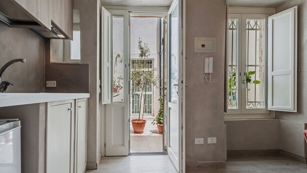 Una cocina estrecha con encimera blanca, armarios y un lavamanos a la vista.