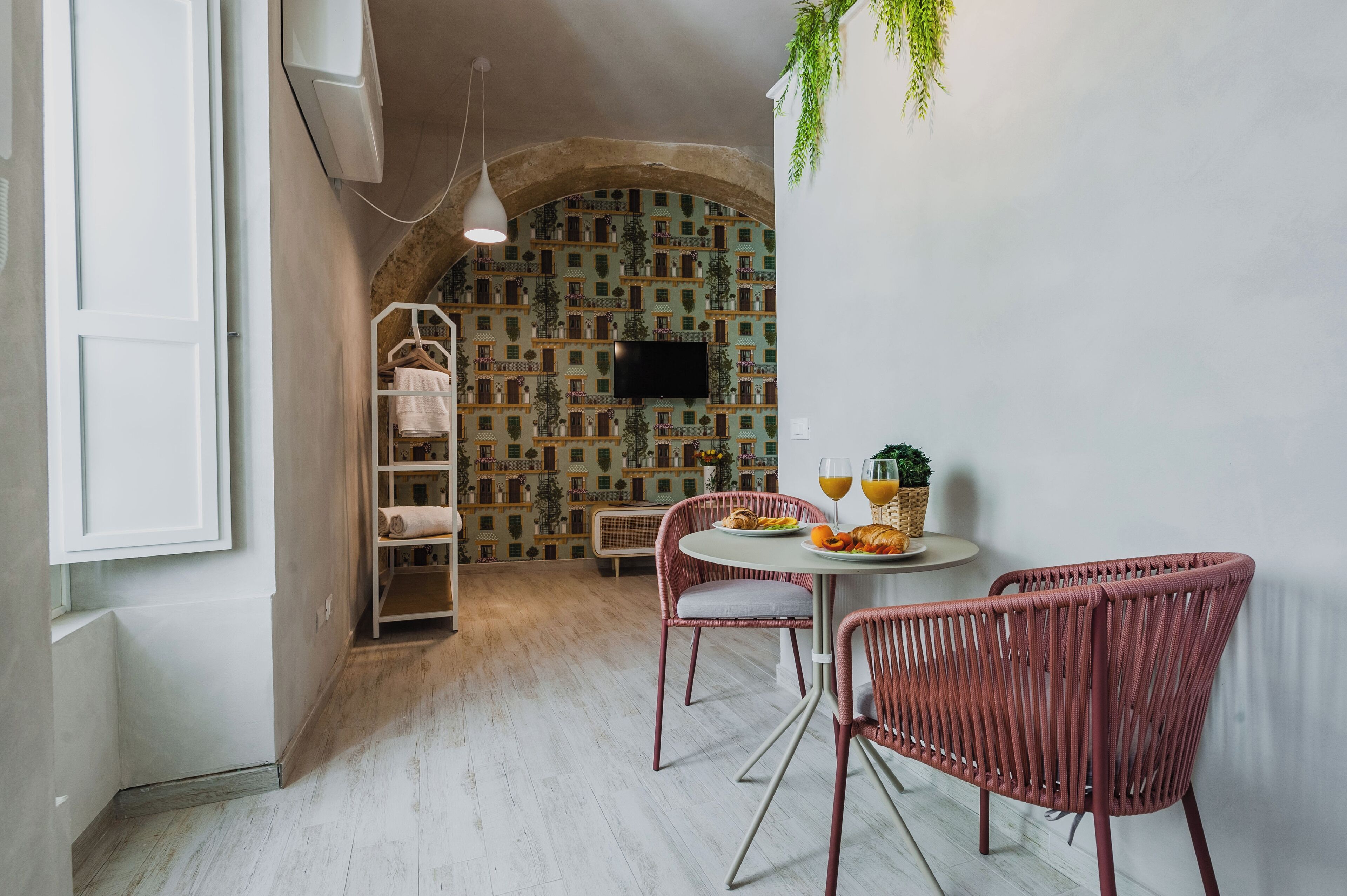 A dining area with wicker chairs, a round table, and a wall with a patterned design.