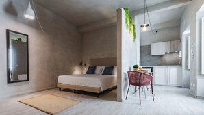 Un dormitorio moderno con cama, mesita de noche y una pequeña zona de comedor con una silla y mesa.