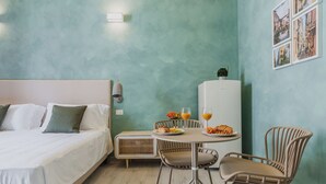 Un dormitorio con cama, mesita de noche y una pequeña zona de comedor con sillas y una mesa.