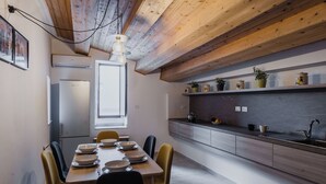 Een moderne keuken met houten balken, een eethoek met een tafel voor vier personen, en een inbouwkast met keukengerei.