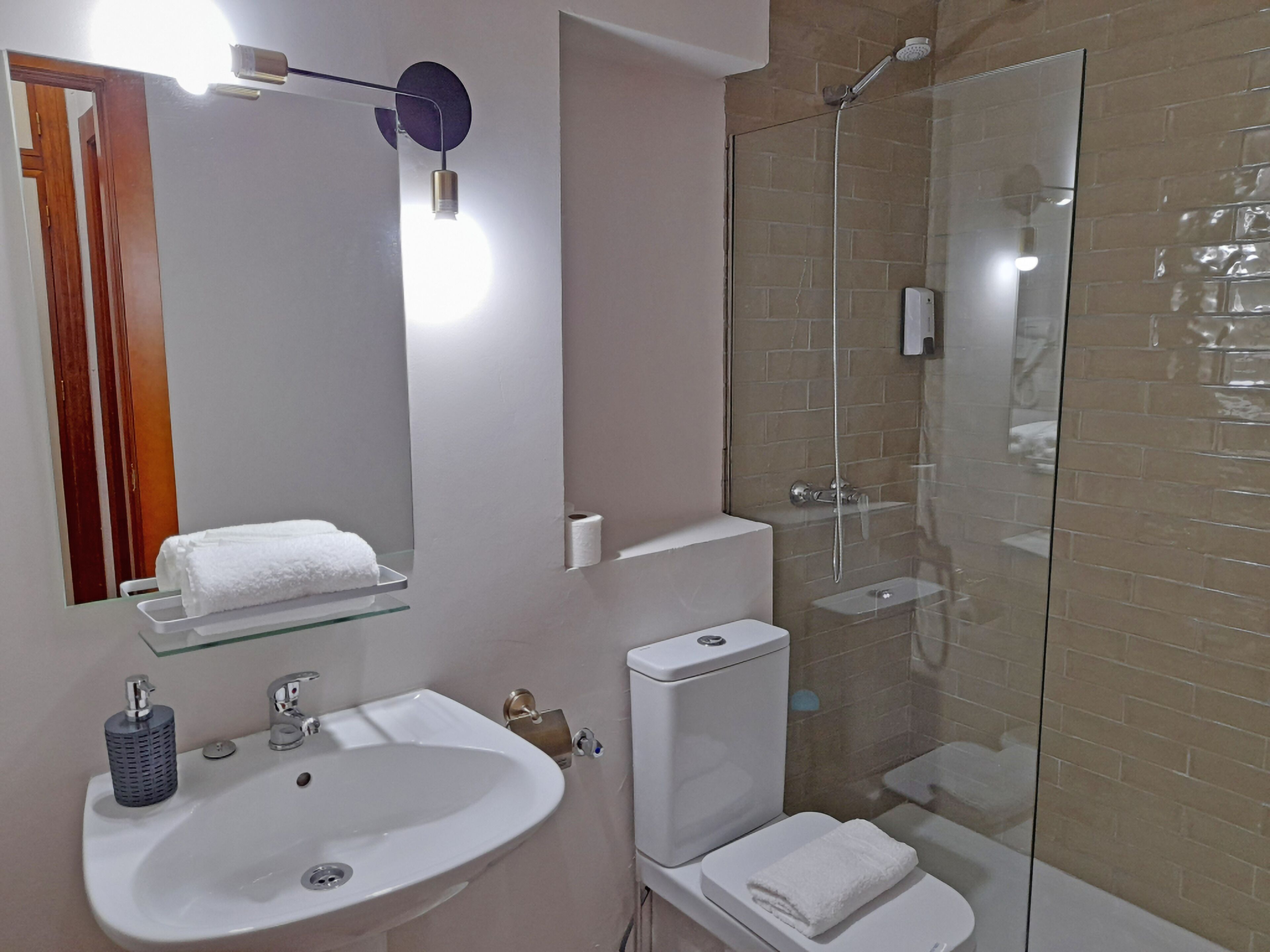 Et badeværelse med vask, toilet og brusekabine.
