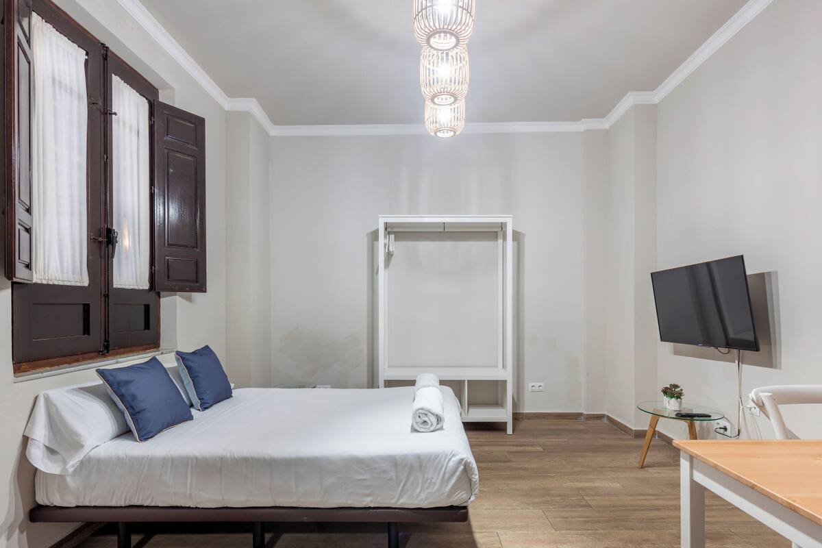 A hotel room with a bed, a television, a desk, and a wardrobe.