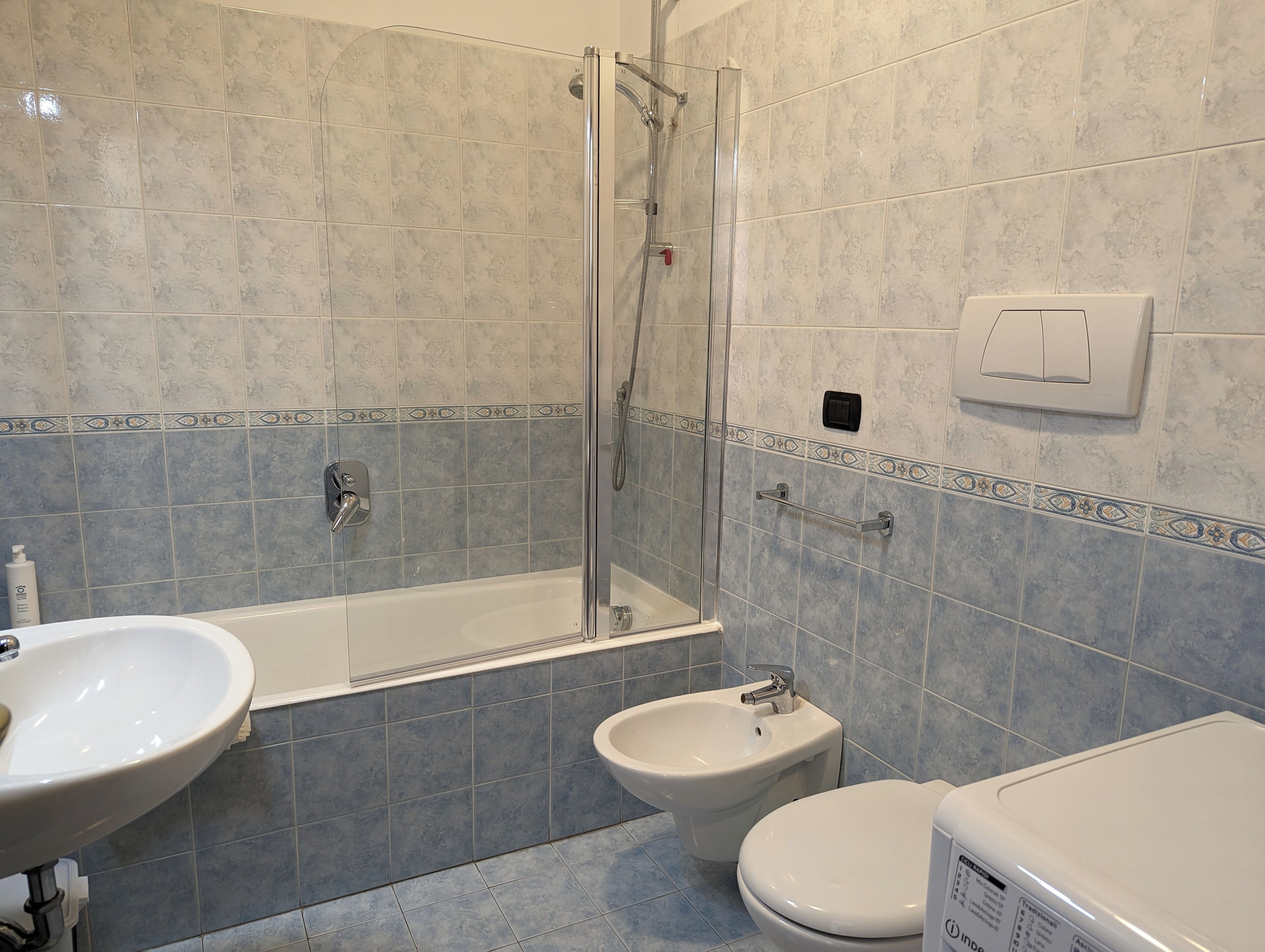Une salle de bain avec une douche à parois de verre, un lavabo, un bidet et des toilettes.