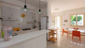 Una cocina moderna con armarios blancos, una estufa de acero inoxidable y un carrito de madera.