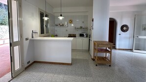 Una cocina moderna con gabinetes blancos, una isla central e iluminación colgante.