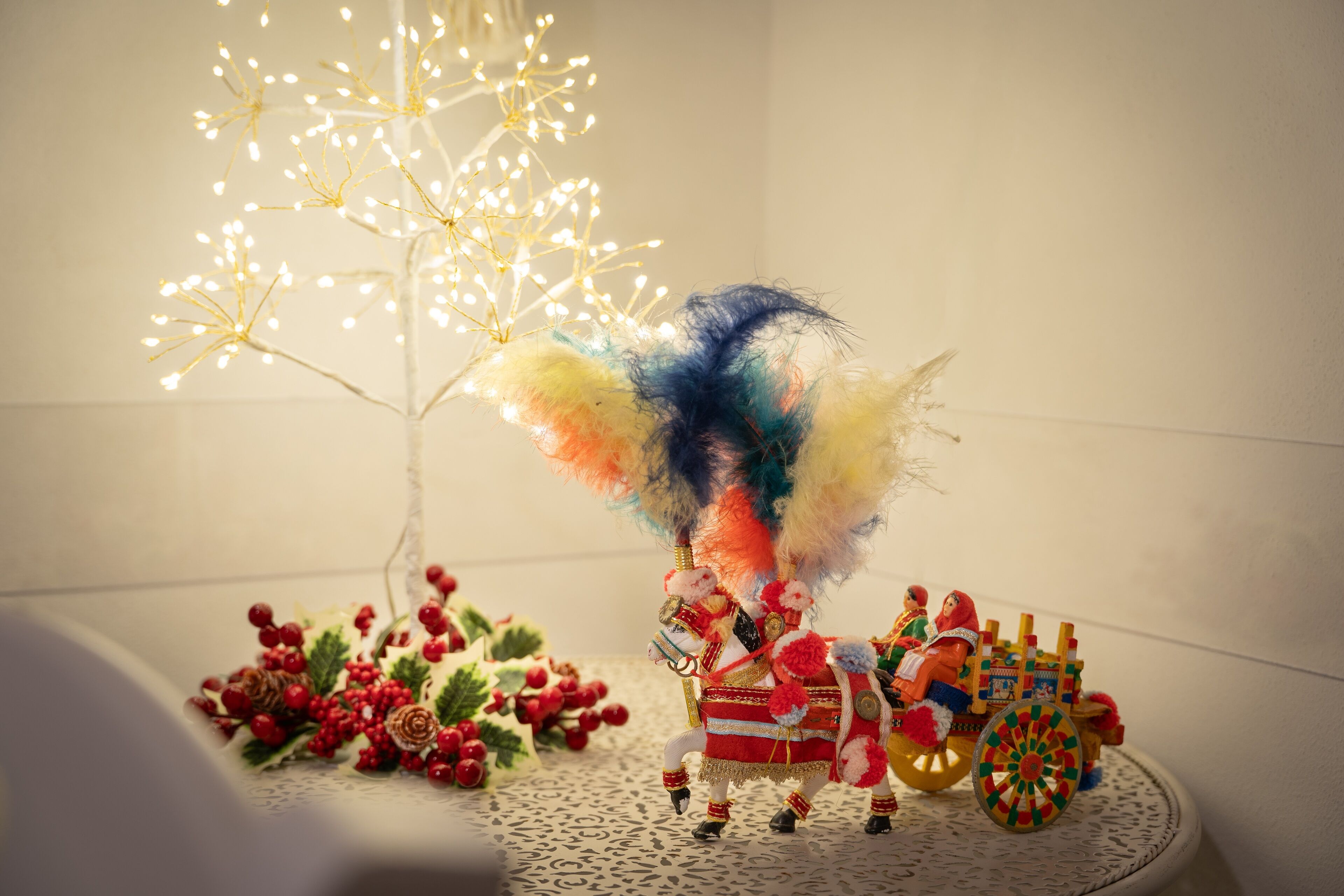 Un árbol de Navidad decorado con luces y una escena colorida y fantástica con un carruaje tirado por caballos.
