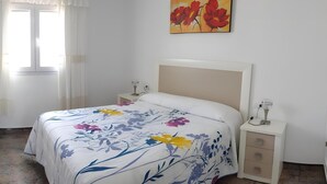 Een slaapkamer met een bed, nachtkastjes, een schilderij en een raam met gordijnen.