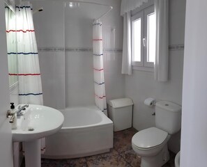 A bathroom with a bathtub, toilet, and sink. - Apartamento con terraza cerca a la playa (Conil de la Frontera)
