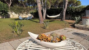 A patio area with a metal table, a potted plant, and a hammock.