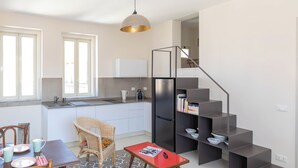 A compact living space with a kitchen, dining area, and a staircase leading to an upper level. - Ortigia Terrazza Su Due Mari by Ortigia Apartm... (Syracuse)