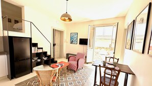 A compact living space with a kitchenette, dining area, and a view through a large window. - Ortigia Terrazza Su Due Mari by Ortigia Apartm... (Syracuse)