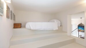 A staircase leading to a bedroom with a bed, a wooden chest, and framed pictures on the wall. - Ortigia Terrazza Su Due Mari by Ortigia Apartm... (Syracuse)