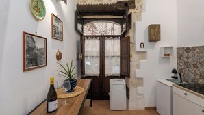 Angolo cottura compatto con un tavolo di legno, una bottiglia di vino e una pianta in vaso.