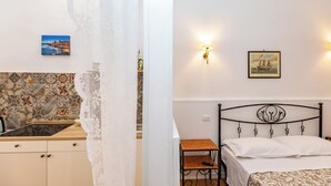 Una camera da letto con un letto, un comodino, una lampada a muro e un quadro.