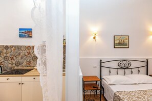 Ein Schlafzimmer mit einem Bett, einem Nachttisch, einer Wandlampe und einem Gemälde.