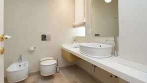A modern bathroom with a white sink, a bidet, and a toilet. - Marina Homes Elegant designroom1 Ortigiapartments (Syracuse)