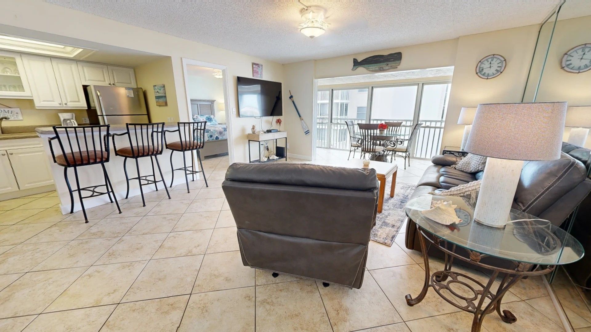 A living room with a sofa, a glass coffee table, and a dining area with chairs and a table.