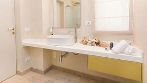 Een moderne badkamer met een witte wastafel, een spiegel en een raam.
