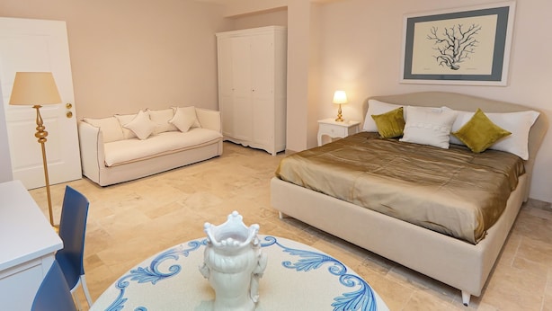 Een slaapkamer met een bed, een bank, een kledingkast, een nachtkastje en een tafel met een decoratief object.