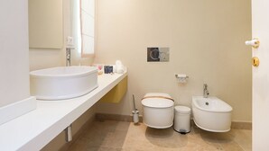 Een moderne badkamer met een groot wit wastafelmeubel, een toilet en een douchetoilet.
