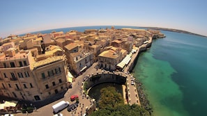An aerial view of a coastal town with historic buildings, a prominent archway, and a clear view of the sea. - SeaChilly House by Ortigiaapartments (Syracuse)