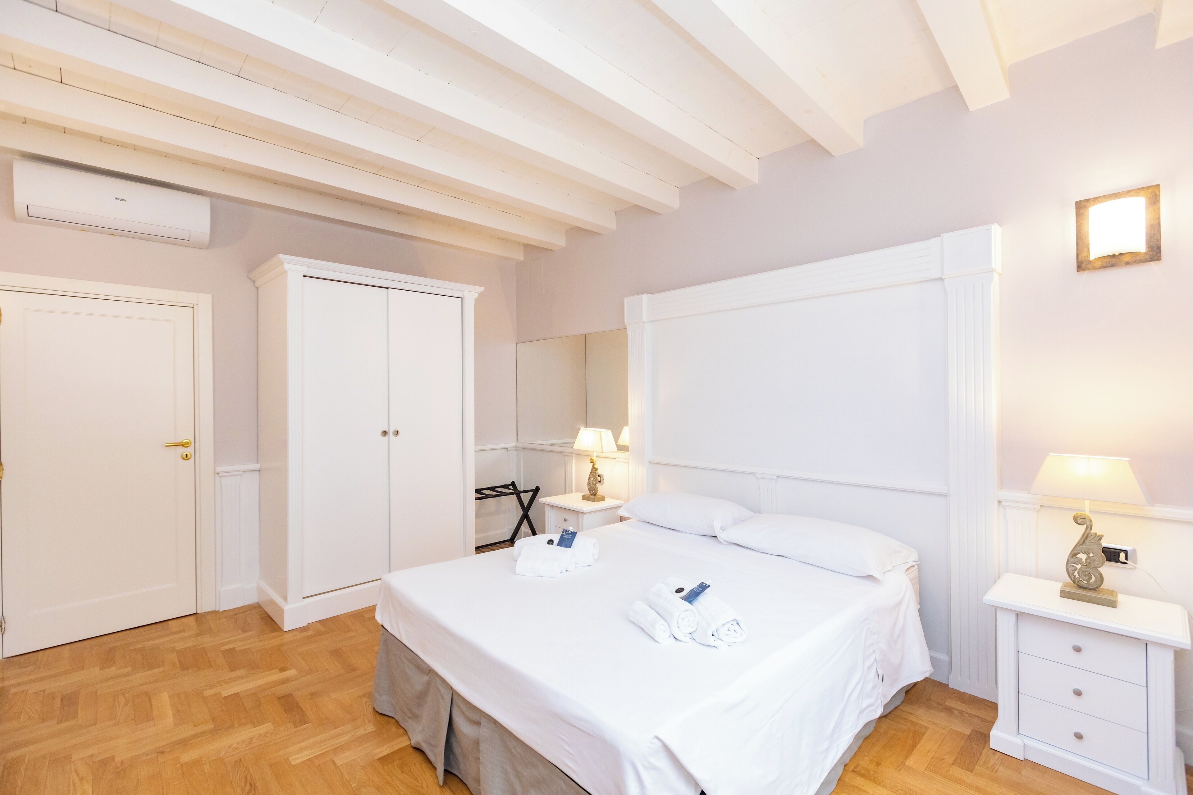 Een slaapkamer met een bed, nachtkastjes, een kledingkast en een airconditioner.