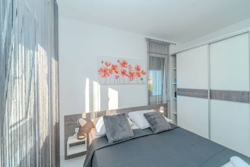 Une chambre moderne avec un lit, une table de chevet et une œuvre d’art accrochée au mur.