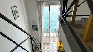 Una escalera conduce a un balcón con piso a cuadros y vista al mar.