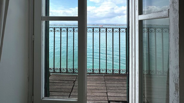 Habitación con vista al mar a través de un balcón con barandilla metálica.