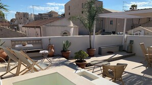 A rooftop pool area with lounge chairs, potted plants, and a small pool. - Terrazza Cavalieri di Malta by Ortigiapartments (Syracuse)