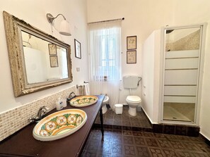 Ein Badezimmer mit einem großen Spiegel, zwei Waschbecken, einer Toilette und einer Dusche.
