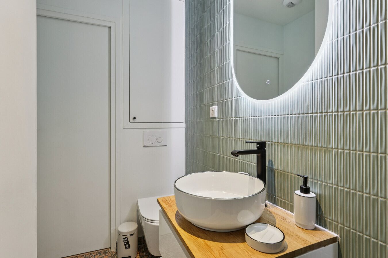 A modern bathroom with a round sink, a mirror, and a toilet.